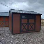 A beautiful Brown and Black 10x12 garden shed with transom windows in the double barn doors.