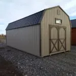 A pretty Buckskin and Dark Brown 12x24 barn with a transom window in the gable and double barn doors beneath the window.