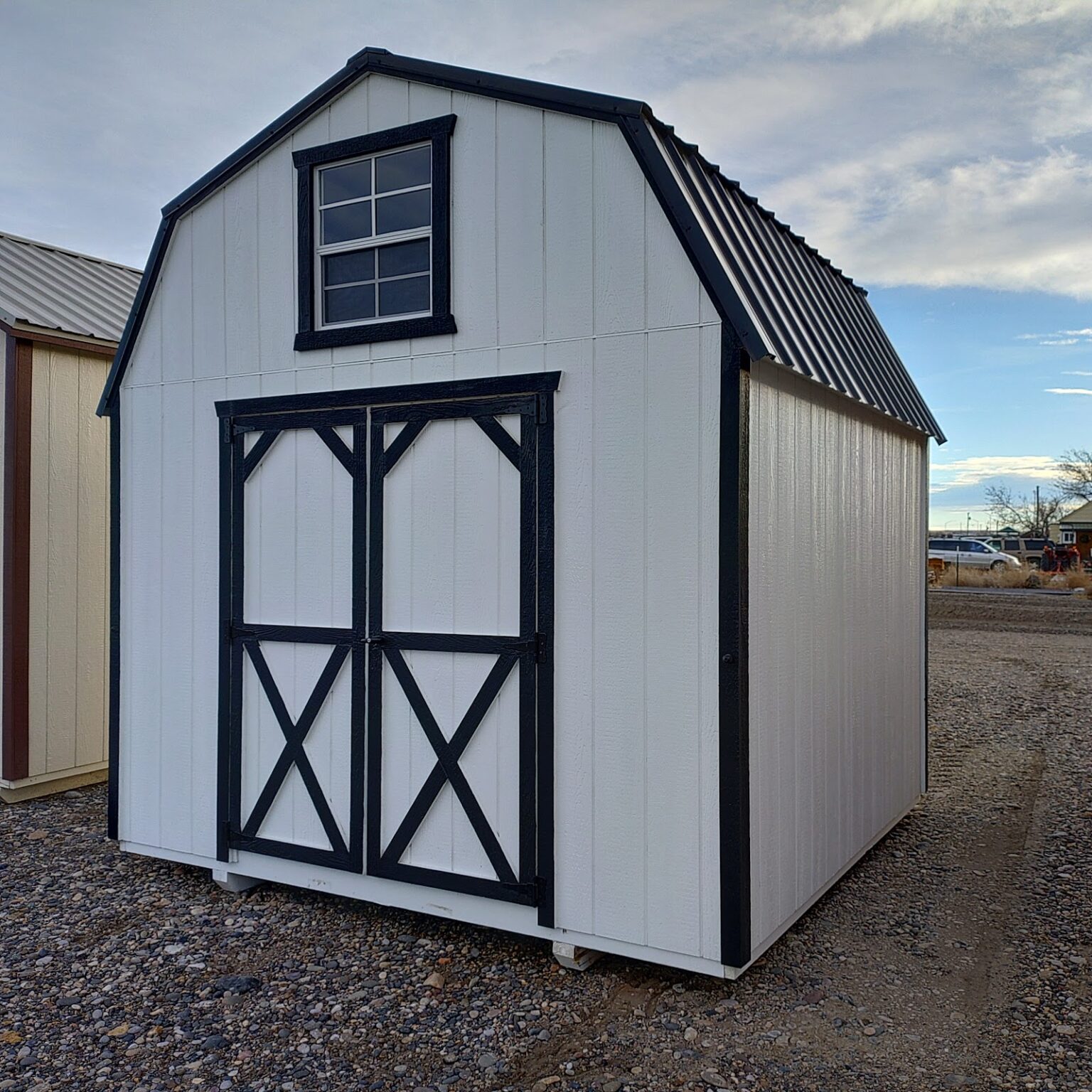 A classy White and Black 10x10 barn with a window in the gable and double barn doors beneath the window.