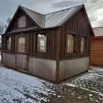 A gorgeous 10x16 rustic greenhouse with lots of windows, sky lights, board-n-bat siding, and a rusted metal wainscot.